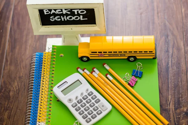 Material escolar, lápices, autobús escolar de juguete, cuaderno, calculadora — Foto de Stock