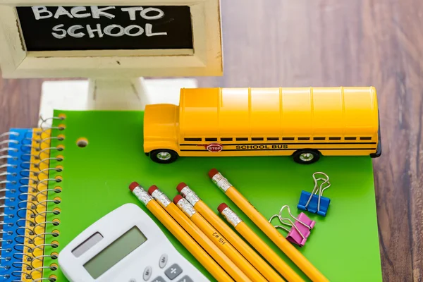 Material escolar, lápices, autobús escolar de juguete, cuaderno, calculadora — Foto de Stock
