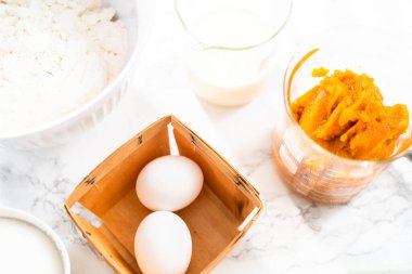 Mermer tezgahta balkabağı baharatlı kek pişirmek için gerekli malzemeler..