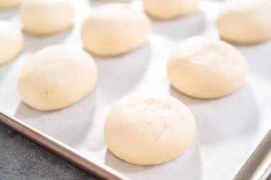 Pişirmeden önce parşömen kağıdıyla kaplanmış fırınlanmış ekmek ruloları..