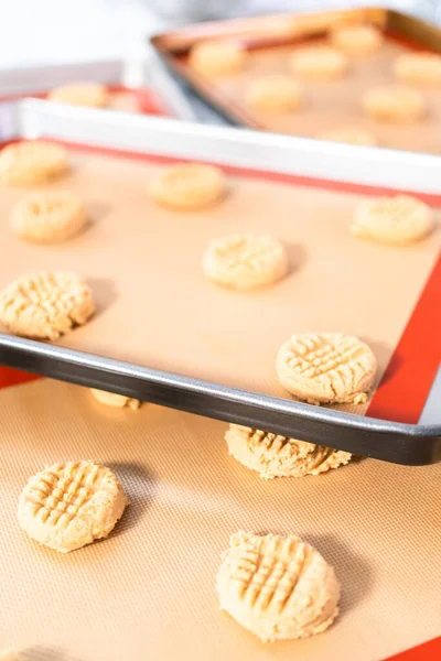 Placing a peanut butter cookie dough on silicone mats for baking.