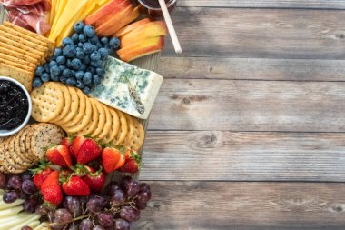 Düz yatıyordu. Aperatif olarak sunulan tahtanın üzerinde gurme peyniri, kraker ve meyve var..