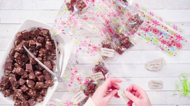 Düz yatıyordu. Adım adım. Ev yapımı macadamia şekerlemesi küçük hediye paketlerine konuyor..