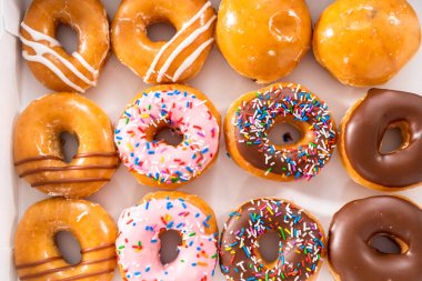 Beyaz bir karton kutuda mağazadan alınmış donutların çeşitliliği.