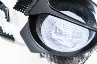 Siyah plastik bir kasede beyaz arka planda saç boyası tozu..