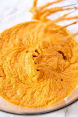 Büyük bir bardakta karıştırılan malzemeler kabaklı kek yapmak için karıştırılıyor..