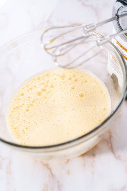 Elmalı Sharlotka keki pişirmek için karışımı büyük bir bardakta karıştırıyorum..