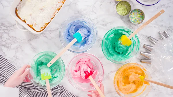 Mixing food coloring into Italian buttercream frosting.