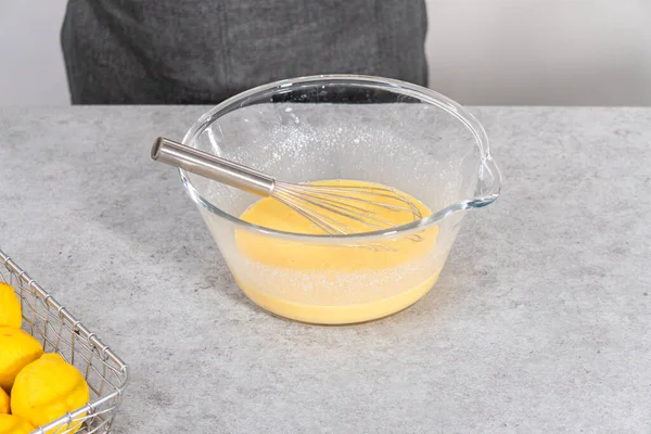 Mixing ingredients in a glass mixing bowl to prepare lemon cranberry bundt cake.