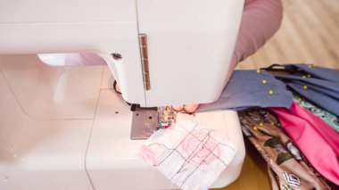 Koronavirüs salgını için dikiş makinesiyle pamuk yüz maskesi dikiyorum..