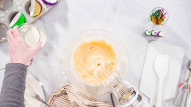 Düz yatıyordu. Adım adım. Vanilyalı Mardi Gras kekleri pişirmek için karışımı elektrikli mikserle karıştırıyorum..