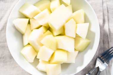 Beyaz bir kasede dilimlenmiş altın çiğ taneli kavun..