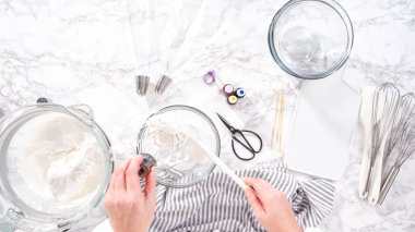 Adım adım. Düz yatıyordu. Tek boynuzlu at kurabiyesi pişirmek için besin boyasını kremaya karıştırıyorum..