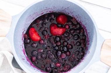 Donmuş böğürtlenlerin karışımını yapışmaz bir tencerede hazırlıyorum..