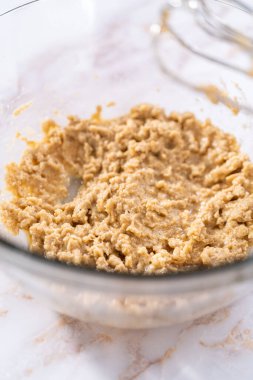 Elmalı yulaflı kurabiye pişirmek için büyük bir bardakta karıştırma malzemesi..