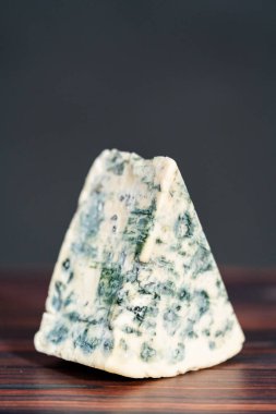 Koyu ahşap arka planda büyük bir dilim mavi peynir..