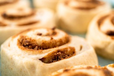 Fırınlanmamış tarçınlı çörekler mavi bir tavada.