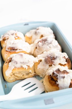 Taze pişmiş tarçınlı rulo, beyaz kremalı, mavi bir tavada..