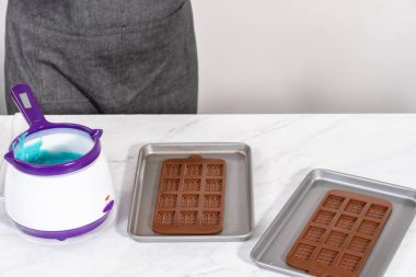 Çikolata kalıplarını erimiş çikolatayla doldurarak küçük denizkızı çikolatalarını hazırlıyorum..