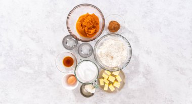 Düz yatıyordu. Bir bardaktaki ölçülü malzemeler tatlı balkabağı ekmeği pişirmek için karıştırılmış kaseler..