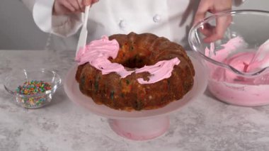 Manzarayı kapat. Dilimlenmiş funfettti demetli kek, üstünde pembe krema ve içinde krema var..