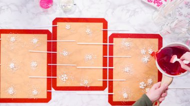 Düz yatıyordu. Ev yapımı lolipoplar yapmak için silikon paspaslara karamelize şeker dökmek..