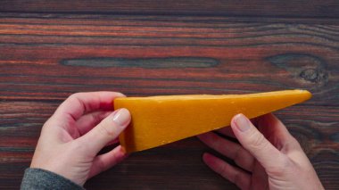 Düz yatıyordu. Büyük bir dilim füme gouda peyniri, ahşap arka planda..