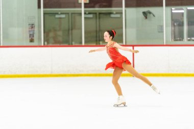 Genç kız buz pateni pistinde artistik patinaj yapıyor..