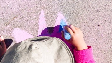 Yaz günü kaldırımda tebeşirle çizen küçük kız..