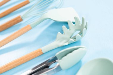 Mavi arka planda ahşap saplı yeni mavi silikon mutfak aletleri..