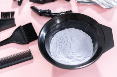 Siyah plastik bir kasede pembe arka planda saç boyası tozu..