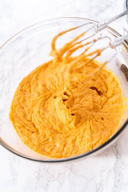 Büyük bir bardakta karıştırılan malzemeler kabaklı kek yapmak için karıştırılıyor..