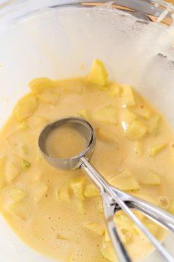 Sharlotka çörekleri pişirmek için parşömen kağıtlarıyla kaplanmış kek tavasına hamur atıyorlar..