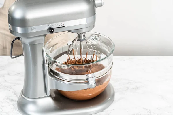 Whipping chocolate ganache with an electric kitchen mixer.