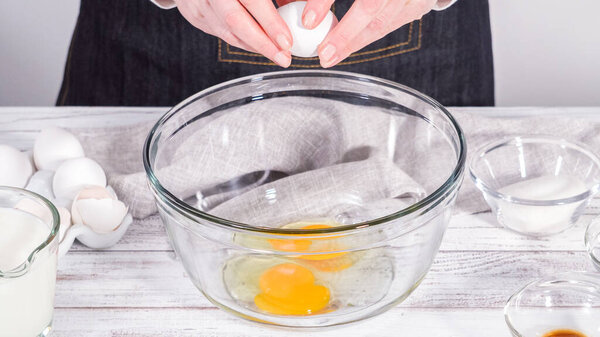 Step by step. Mixing ingredients in a large glass mixing bowl to prepare French toast.