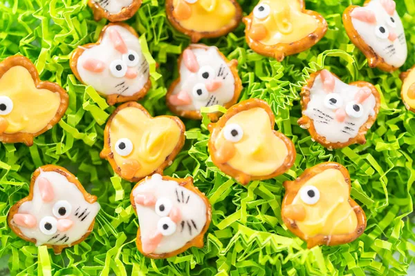 Easter chocolate-covered pretzel bunnies and ducklings on green Easter grass.