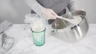 Tek boynuzlu at meringue kurabiyesi pişirmek için metal uçlu boru torbalarına krema karıştırılıyor..