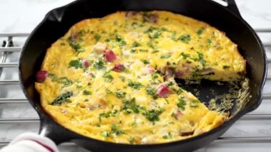 Beyaz bir yemek tabağında ıspanak ve jambonlu frittata..
