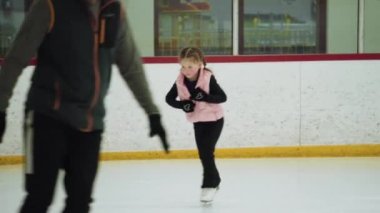 Küçük kız buz pateni pistinde artistik patinaj yapıyor..