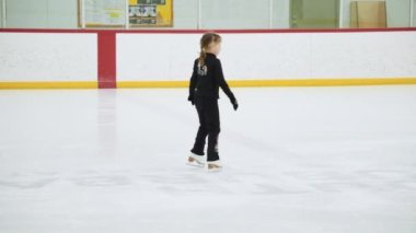 Küçük kız buz pateni pistinde artistik patinaj yapıyor..