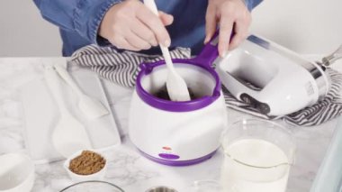 Çikolata erir, şeker tenceresinde erir. Gurme mini çikolatalar hazırlamak için çikolata serpiştirir..