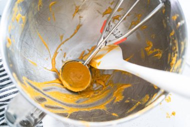 Kirli spatula ve hamur kepçesi metal karıştırma kabında.