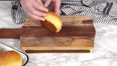 Odun kesme tahtasının üzerinde taze pişmiş çörekleri dilimliyorum..