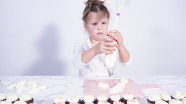 Adım adım. Küçük kız kesme tahtasına tereyağı kreması sürme alıştırması yapıyor.