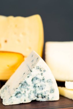 Koyu ahşap arka planda büyük gurme peynir dilimleri var..