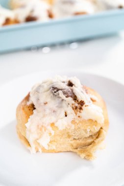 Taze pişmiş tarçınlı rulo, beyaz kremalı, mavi bir tavada..