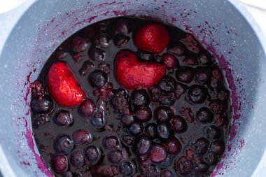 Donmuş böğürtlenlerin karışımını yapışmaz bir tencerede hazırlıyorum..