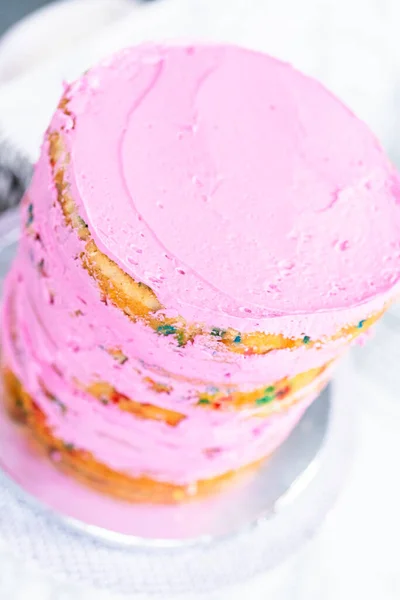 ピンクのバタークリームの霜降りとFunfettiケーキ層 — ストック写真
