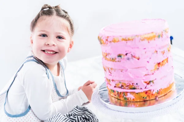 Mała Dziewczynka Pomaga Upiec Wysoki Funfetti Ciasto Różowym Lukrem Maślany — Zdjęcie stockowe