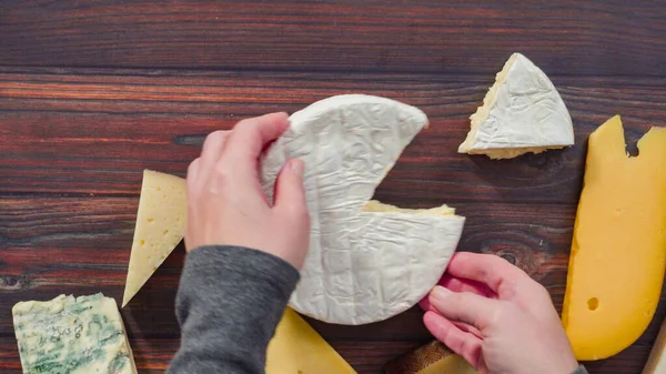 Flat lay. Large wedges of gourmet cheese on a rustic wood background.